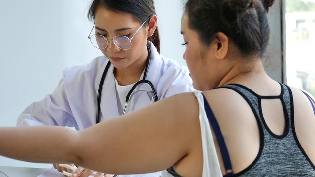 THe young pretty smiling medical Asian doctor giving advise to a overweight fat woman to prevent COVID-19 virus pandemic in clinic hospital 
