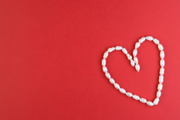 white pearl heart on a red background, top view