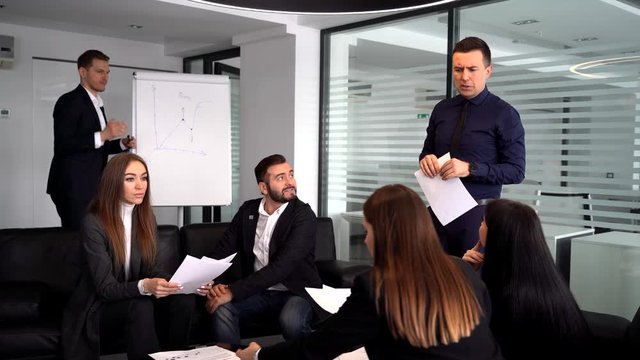 Smiling millennial male coach or presenter make flip chart presentation ask question during work training