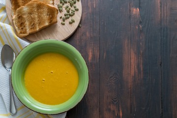 Vegetarian homemade pumpkin cream soup with seeds and bread,top view.
