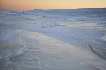 Evening view of a frozen water of a gulf covered with ice and snow