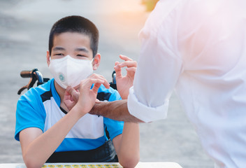 Asian special child on wheelchair wearing a protection mask by adult, Against PM 2.5 air pollution and flu Covid 19 or Coronavirus, Stay at home to prevent the spread of the virus disease 2020.