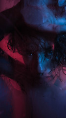 man with a sad look looking at the camera, with red and blue lights