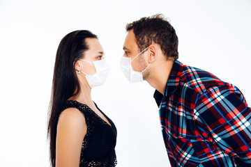 Violation of distance under quarantine. Husband and wife in surgical masks on a white background are looking at each other. Coronavirus.