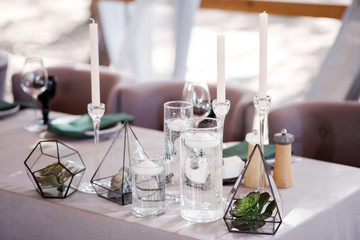 Festive wedding table setting with flowers, napkins, cutlery, glasses and candles, bright summer table decor. Wedding decor