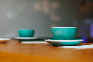 Close up of hot tasty fresh cappuccino on wooden table with napkins in greenery ceramic cup with blur background. Morning hot drinks made by professional barista for client.