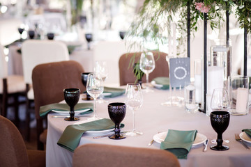 Festive wedding table setting with flowers, napkins, cutlery, glasses and candles, bright summer table decor. Wedding decor