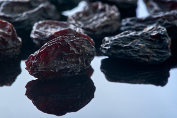group raisins lies on on a black glass reflective surface. macro shot. background.