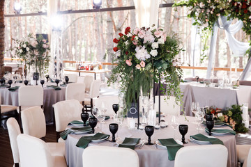 Festive wedding table setting with flowers, napkins, cutlery, glasses and candles, bright summer table decor. Wedding decor