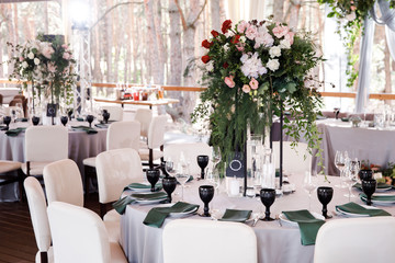 Fototapeta na wymiar Festive wedding table setting with flowers, napkins, cutlery, glasses and candles, bright summer table decor. Wedding decor