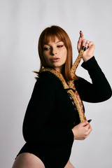 Beautiful woman in black bodywear and snake. Ginger model girl with fashion perfect make up.
