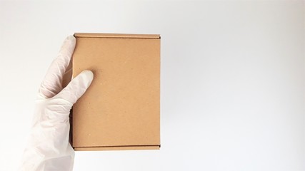 Courier's hands in latex white medical gloves deliver parcels in brown cardboard boxes to the door during the epidemic of coronovirus,COVID-19.Safe delivery of online orders during the epidemic.