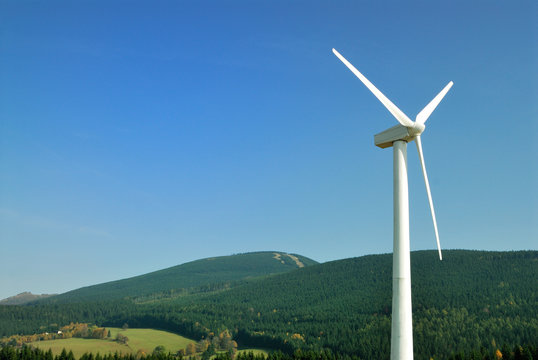 Energy wind turbine in front of mountains and blue sky