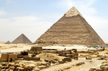 Fototapeta na wymiar Giza Pyramids with stones and little beduin travelling on camel in front