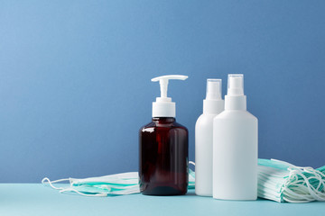Coronavirus protection. Medical surgical masks, sanitizer gel for hand, spray on blue background. Space for text.