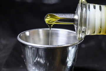 Pouring olive oil in metal cup