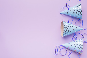 Birthday hat and silver serpentine on a purple paper background. Decoration party. Holiday background. Copy space