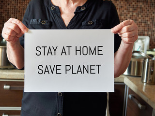 the hands of an old woman hold a white sheet with the text: stay at home, save planet. coronavirus, covid-19.