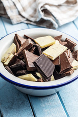 Broken white, milk and dark chocolate bars in bowl