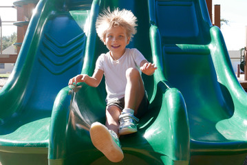 Smiling boy going down a slide with hair sticking up due to static electricity