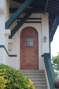 Porta de entrada em madeira com um postigo num alpendre de madeira de uma casa