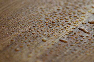 Drops water are sprayed on dark wooden surface. Close-up condensate. Plumbing broke through in apartment. Wooden surface furniture after summer rain. Cleaning agent sprayed on laminate