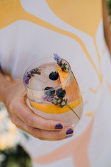 Copa con bebida alcohólica, naranja, lavanda y arándanos