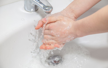Woman washes her hands with soap under the water tap. Hygiene consept hand detail.