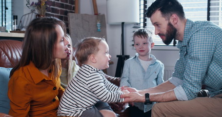Obraz premium Family bonding time concept, young European parents play with little child joining hands and having fun slow motion.