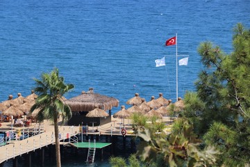 Turkish flag on a flagpole in the background hotel beach and the Mediterranean sea