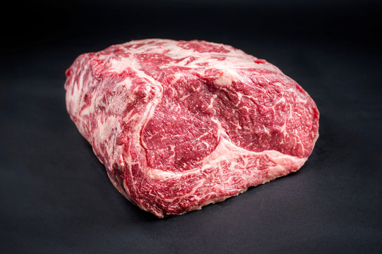 Raw dry aged wagyu entrecote beef steak roast as closeup on a black background with copy space