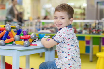 a small boy plays with toys in kindergarten or at home sitting at a table in the children's room
