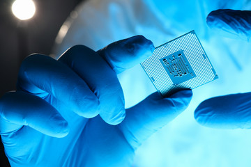 Close-up gloved hands holding detail microchip. Man in special uniform shows microprocessor chip....