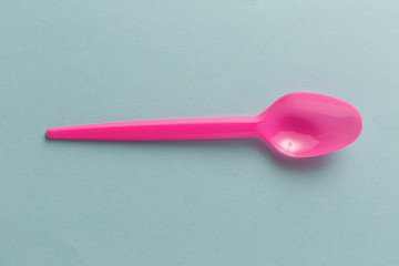 Pink plastic spoon on blue background