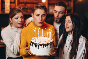young handsome man holding a cake which he gave his friends for his birthday. Birthday celebration with best friends