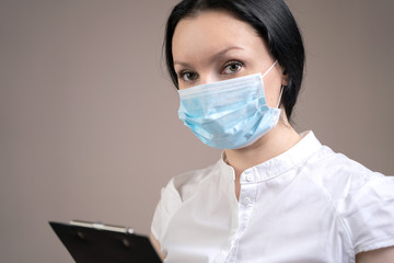 Girl doctor in rubber gloves and a medical mask with a tablet, the concept of preventing the spread of coronavirus.