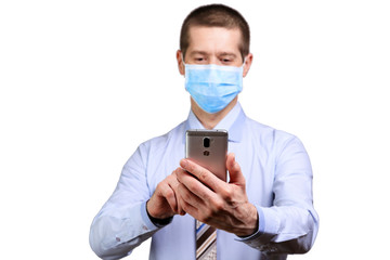 Happy man in medical mask, shirt, tie, holding phone in front of him, dialling text, isolated