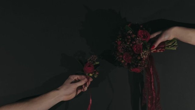 Hands on a black background with a red bouquet and men's with a buttonhole as in the picture of Creation of Adam by Michelangelo