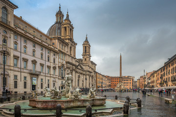 Fototapeta na wymiar Przepięknie rzeźbione fontanny oraz katedra na Piazza Navonna w Rzymie. Pochmurny i deszczowy dzień. Włochy, Europa