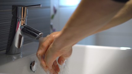 Coronavirus infection prevention. Person washing hands with soap and water, detail.