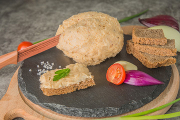 A piece of melted lard, on slate, with spices and brown bread. One piece of bread is buttered with lard, an appetizer. Knife in a large piece of lard, close-up.