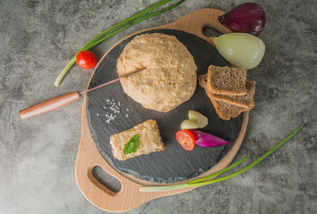 A piece of melted lard, on slate, with spices and brown bread. One piece of bread is buttered with...