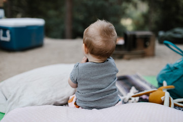 baby playing on the ground at a tent campsite