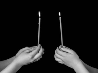 burning church candles in the hands of children on a dark background