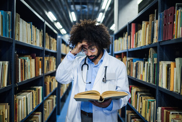 Doctor standing in library, studying information about corona virus.