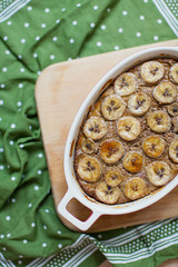Tasty banana bread in a ceramic baking dish on a wooden cutting board