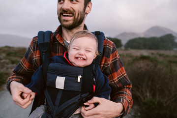father baby-wearing his daughter on a coastal hike