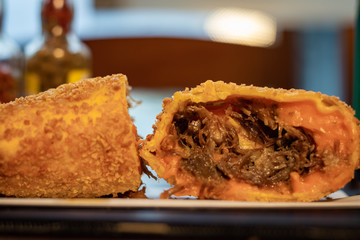 Pastel frito da culinária brasileira de massa crispy com recheio de costela com cheddar encima de guardanapo  com fundo de pimenta 