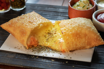 Pastel de quatro queijo com cheddar e mussarela e catupiri e gorgonzola e parmesão em uma mesa com...