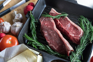 Pieces of fresh meat with butter and rosemary. Juicy beef steaks. Meat with vegetables and spices.